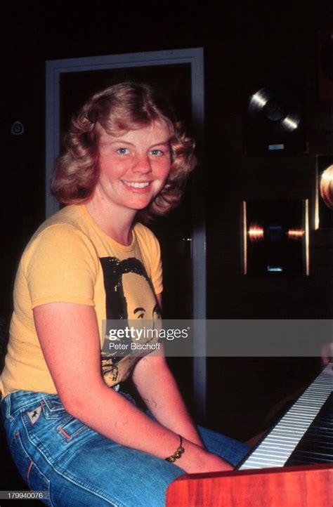 A Woman Sitting At A Piano Smiling And Posing For The Camera With Her