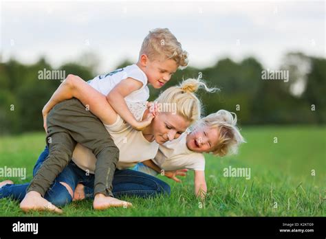 Picture Of A Woman Who Romps With Her Two Sons On The Grass Stock Photo