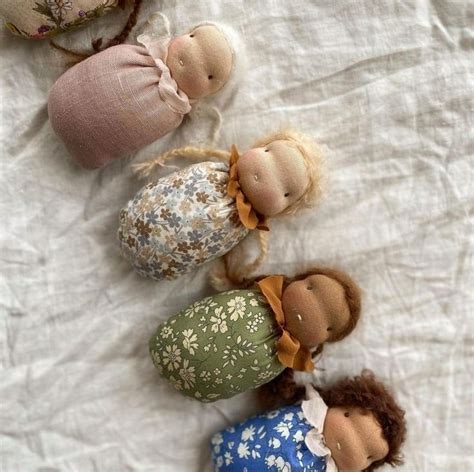 Five Cloth Dolls Laying On Top Of A White Sheet