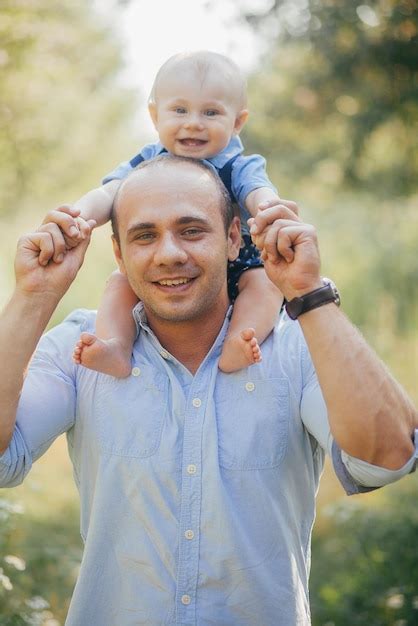 El padre sostiene al pequeño hijo en sus brazos en el parque de verano