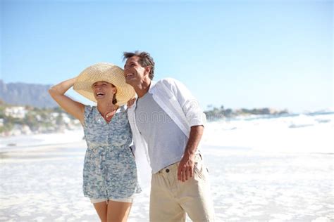 Just Being Together Brings Them Joy A Happy Mature Couple Walking Together On The Beach Stock
