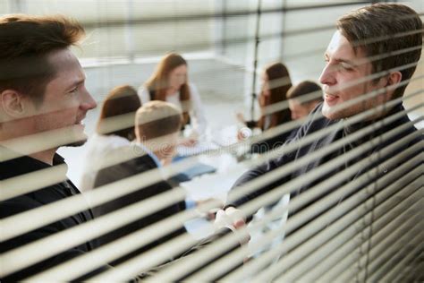 Through The Blinds Business Colleagues Shaking Hands With Each Other