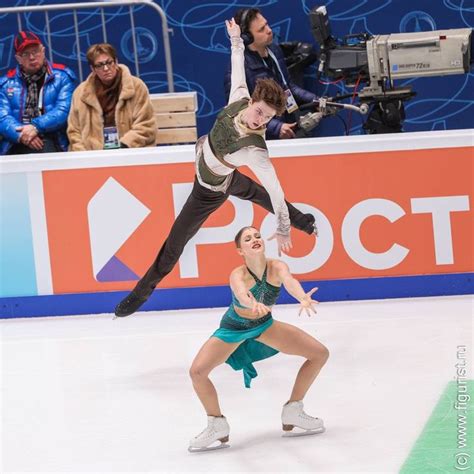 Two People Are Performing On The Ice At An Indoor Skating Rink One Is