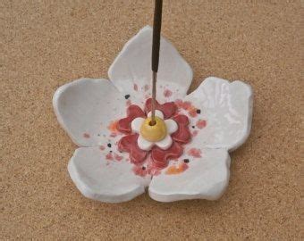 A White Flower Shaped Dish With A Stick Sticking Out Of It