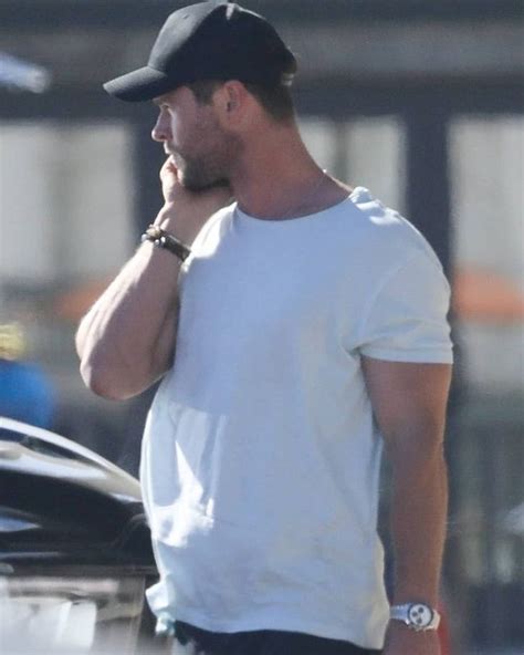 A Man Talking On A Cell Phone While Standing In Front Of A Car With His