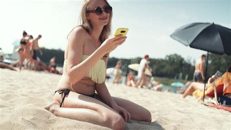 Mujer Bonita En El Bikini Que Se Sienta En La Playa Y Que Toma Un