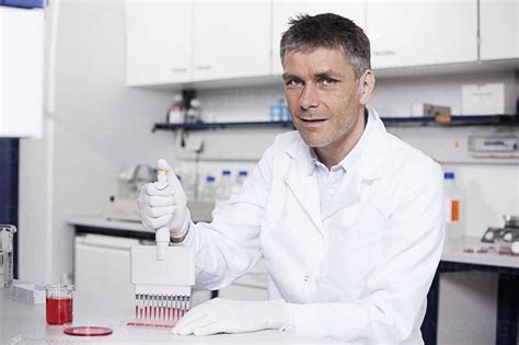 Germany Bavaria Munich Scientist Pouring Red Liquid With Pipette In