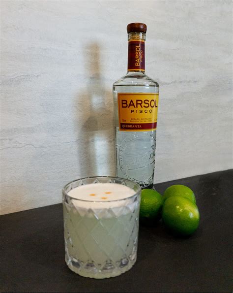 pisco sour cocktail in rocks glass with lime barsol pisco bottle - Le Wild Explorer