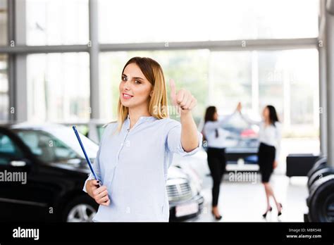 Blonde Business Woman Showing Thumbs Up While Standing In Modern Car Dealership Stock Photo Alamy