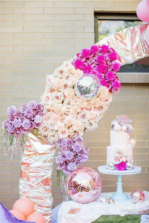 A Table Topped With Lots Of Pink And White Flowers Next To A Tall Vase