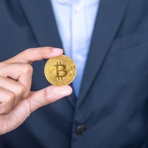 Mão de empresário segurando a criptomoeda Bitcoin BTC dourada