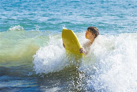 El Muchacho Adolescente Se Divierte El Practicar Surf En Las Ondas