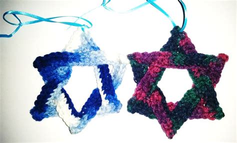 Two Crocheted Ornaments Hanging From Strings On A White Surface One Is