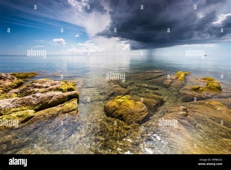 crystal clear water with green mossy stones at Lake Malawi, dark stormy ...