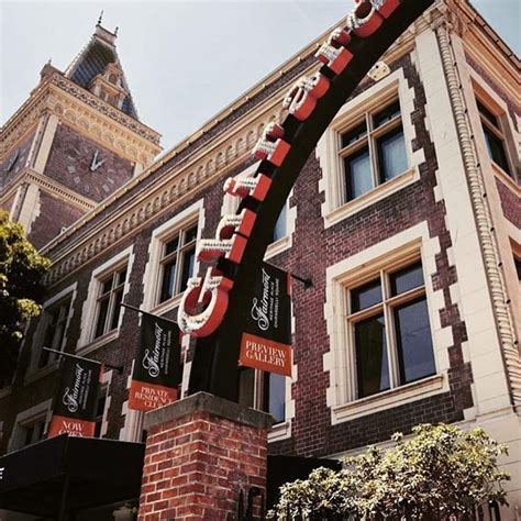 A Large Sign On The Side Of A Brick Building With A Clock Tower In The