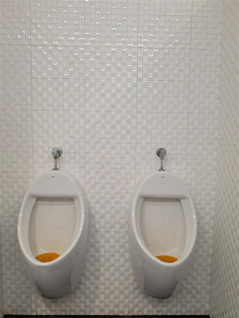 Two Urinals Next To Each Other With A Seperator In Between Stock Image