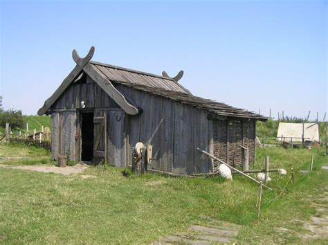 An Old Wooden Shack With Horns On The Roof And Door In A Grassy Field