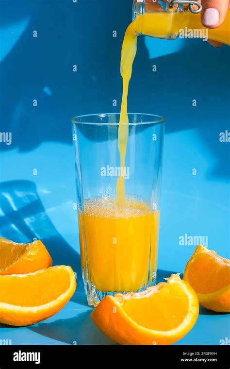 Pouring Orange Juice Stream From Jug Into Glass Of Squeezing Orange