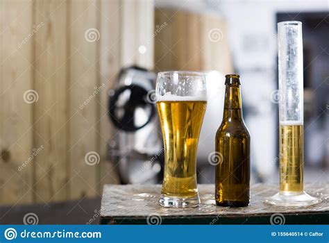 Botella Y Vidrio Con La Cerveza Del Oro En El Fondo De Los Barriles