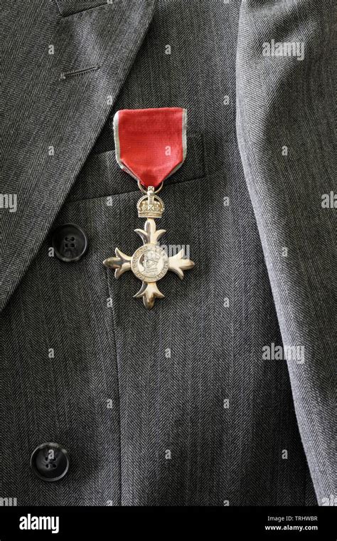 British MBE medal worn on grey suit, Member of the British Empire award life event honours ...