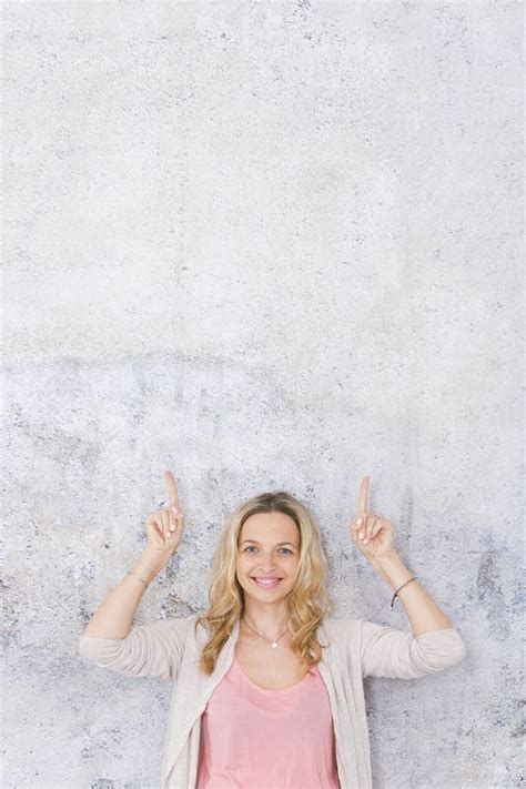 Sch Ne Blonde Frau Zeigt Auf Und Wirft Vor Grau Betonmauerhintergrund Auf Stockfoto Bild Von