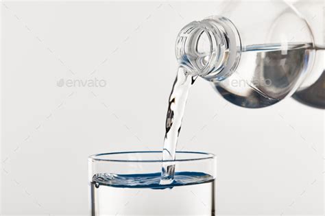 Clear Fresh Water Pouring Into Glass From Bottle Isolated On White