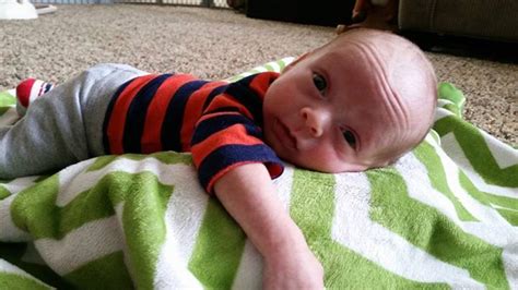 A Baby Laying On Top Of A Green And White Blanket