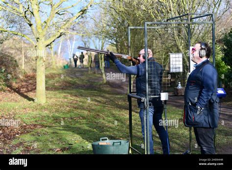 Two Men Clay Pigeon Shooting One Taking Aim Whilst The Other One Is