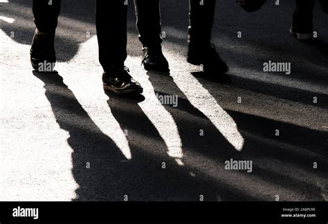 Blurry Shadow Silhouette Of Two People Walking On City Pedestrian