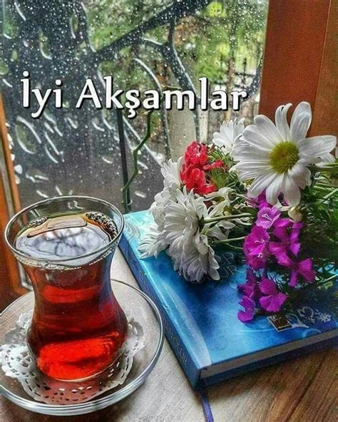 A Cup Of Tea Sitting On Top Of A Table Next To A Book And Vase Filled