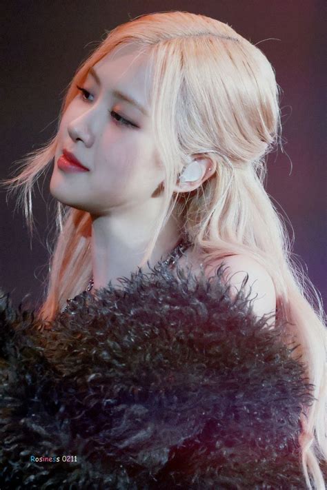 A Woman With Long Blonde Hair Wearing A Black Fur Coat And Ear