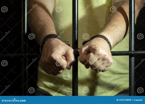 A Man In Handcuffs In A Cell Behind Bars Concept A Prisoner In A