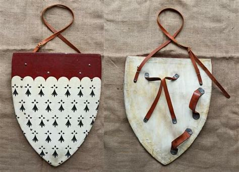 Two Pieces Of Art Made Out Of Wood With Leather Straps Hanging On The