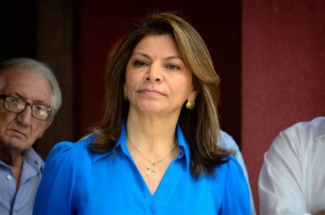 A Woman In Blue Shirt Standing Next To Two Men And One Is Looking Off