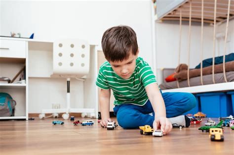 Niño jugando con coches de juguete en casa Foto Premium