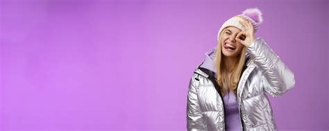 Sympathique joyeuse fille blonde caucasienne en chapeau chaud et élégant veste argentée