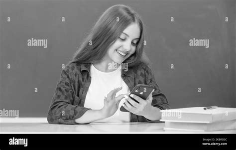 Happy Kid Chatting On Smartphone In Classroom At Blackboard