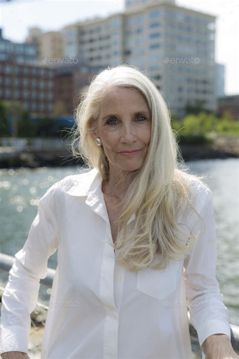 Portrait Of Smiling Mature Woman Wearing White Shirt Blouse Stock Photo