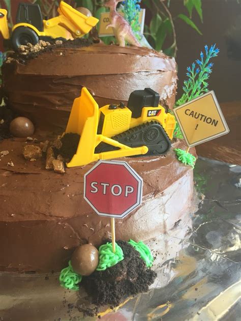 a chocolate cake with construction vehicles on top and a stop sign in the middle that says caution