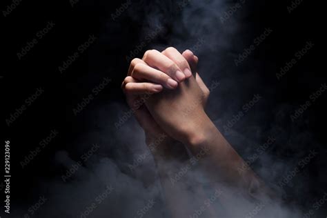 Praying hands over dark background Stock Photo | Adobe Stock