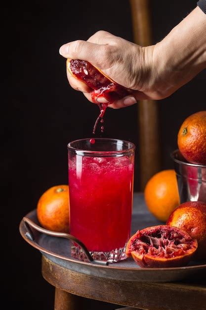 Vaso De Jugo De Naranja Sanguina Con Hielo Y Frutas De Naranja Sobre