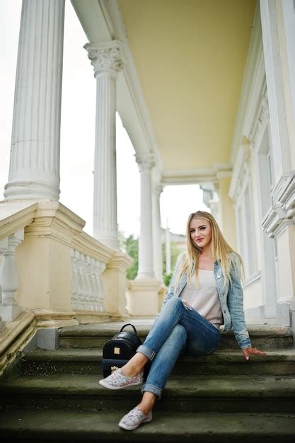 Une Fille Blonde Porte Un Jean Avec Un Sac à Dos Posé Contre Une Maison Vintage Photo Gratuite