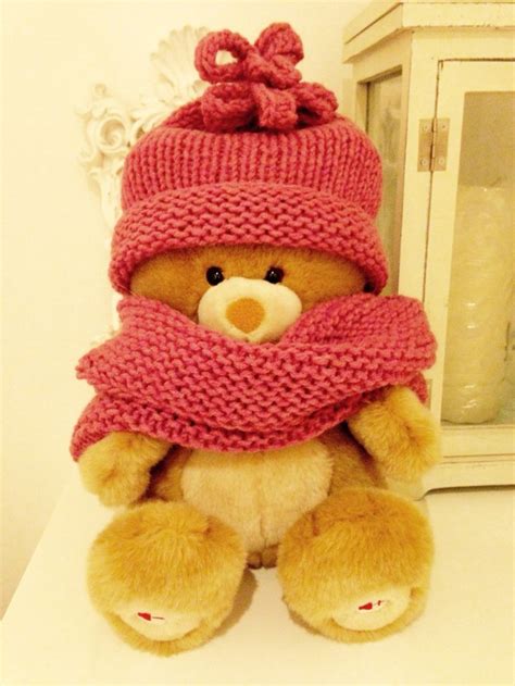 A Brown Teddy Bear Wearing A Pink Hat And Scarf Sitting On Top Of A Table