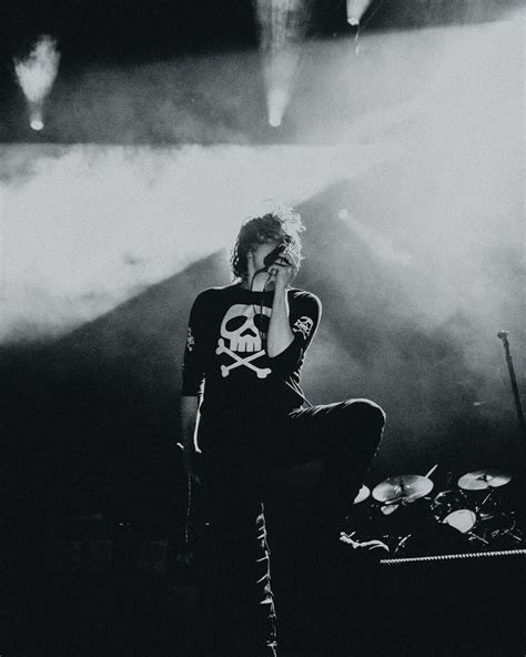 a man sitting on top of a stage next to a drum set in front of him