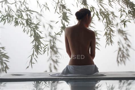 Back View Of Attractive Naked Woman Sitting On Massage Table In Spa