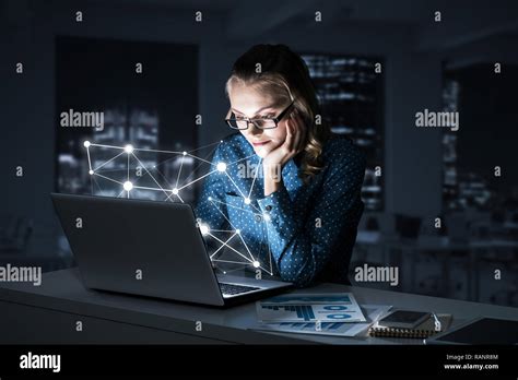 Attractive Blonde Wearing Glasses In Dark Office Using Laptop M Stock Photo Alamy