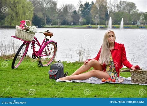 Sexy Rubia En Una Bicicleta En El Parque Con Un Lago En Un Picnic Tumbado En El Césped Foto De