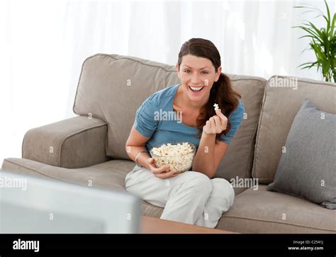 Merry Woman Eating Pop Corn While Watching A Movie On Television Stock