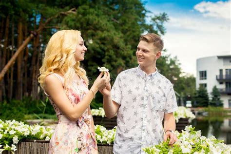 La Jeune Fille Blonde Charmante Et Flirte Avec Un Mec Dans Le Jardin Lovestory D Un Couple