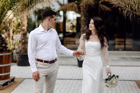 A noiva e o noivo andam de mãos dadas o noivo usa um vestido branco